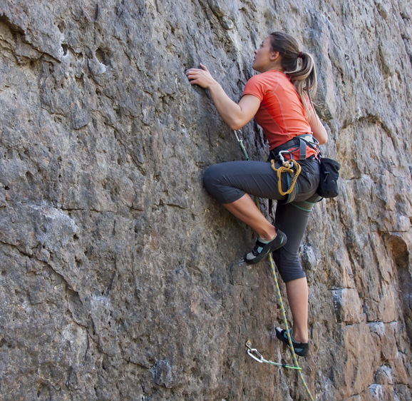 A young woman with a rope engaged in the sports of rock climbing on the rock. A young woman with a rope engaged in the sports of rock climbing on the rock.