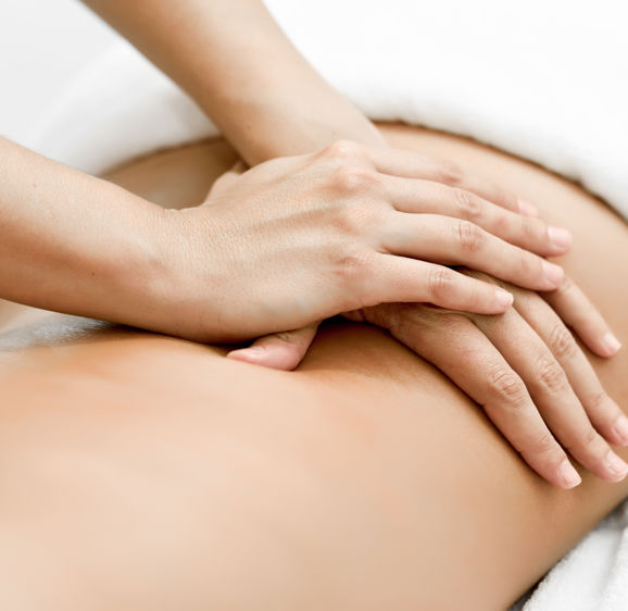 Young woman receiving a back massage in a spa center. Female patient is receiving treatment by professional therapist Young woman receiving a back massage in a spa center. Female patient is receiving treatment by professional therapist