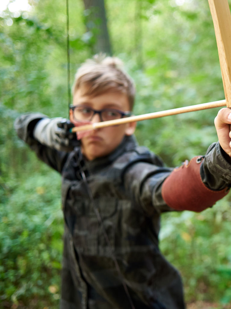 Boy teenager has training, shoots a wooden bow in the forest Boy teenager has training, shoots a wooden bow in the forest