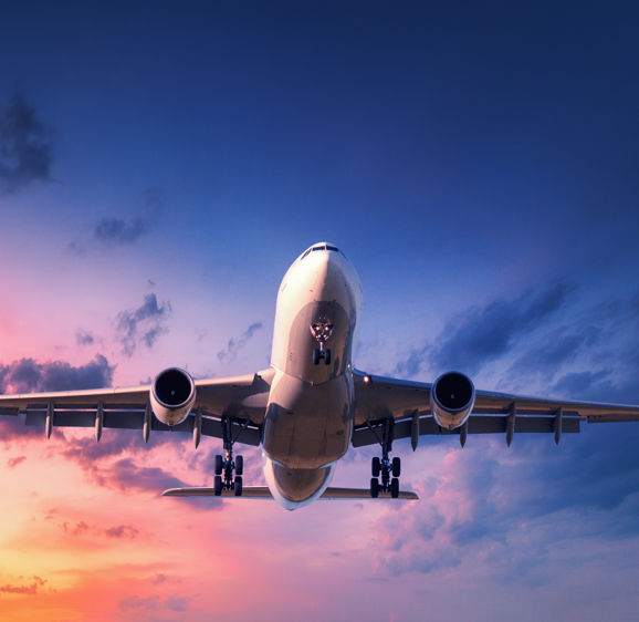 Landing airplane against colorful sky at sunset Landing airplane against colorful sky at sunset