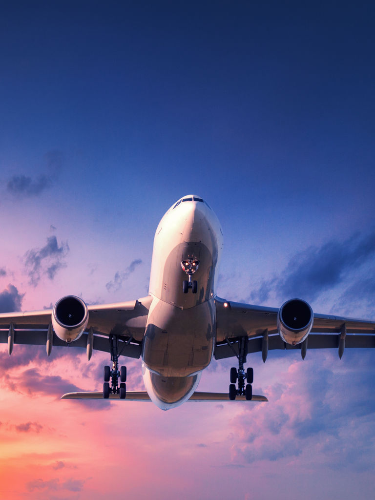 Landing airplane against colorful sky at sunset Landing airplane against colorful sky at sunset