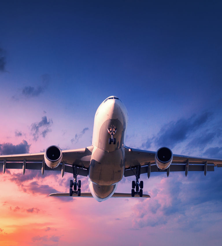 Landing airplane against colorful sky at sunset Landing airplane against colorful sky at sunset
