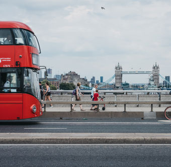 Cyclist, pedestrians and double decker bus on London Bridge, London, UK, River Thames and Tower Bridge on the background. Cycling is a popular way to get around the city. Cyclist, pedestrians and double decker bus on London Bridge, London, UK, River Thames and Tower Bridge on the background. Cycling is a popular way to get around the city.