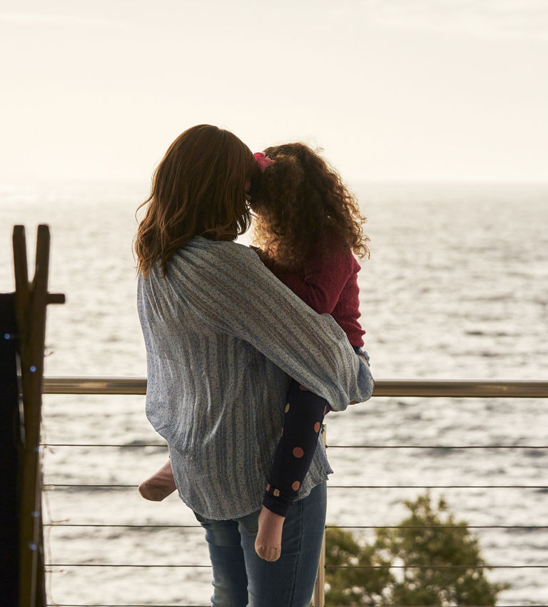 Mom holding daughter on balcony looking at the ocean Mom holding daughter on balcony looking at the ocean
