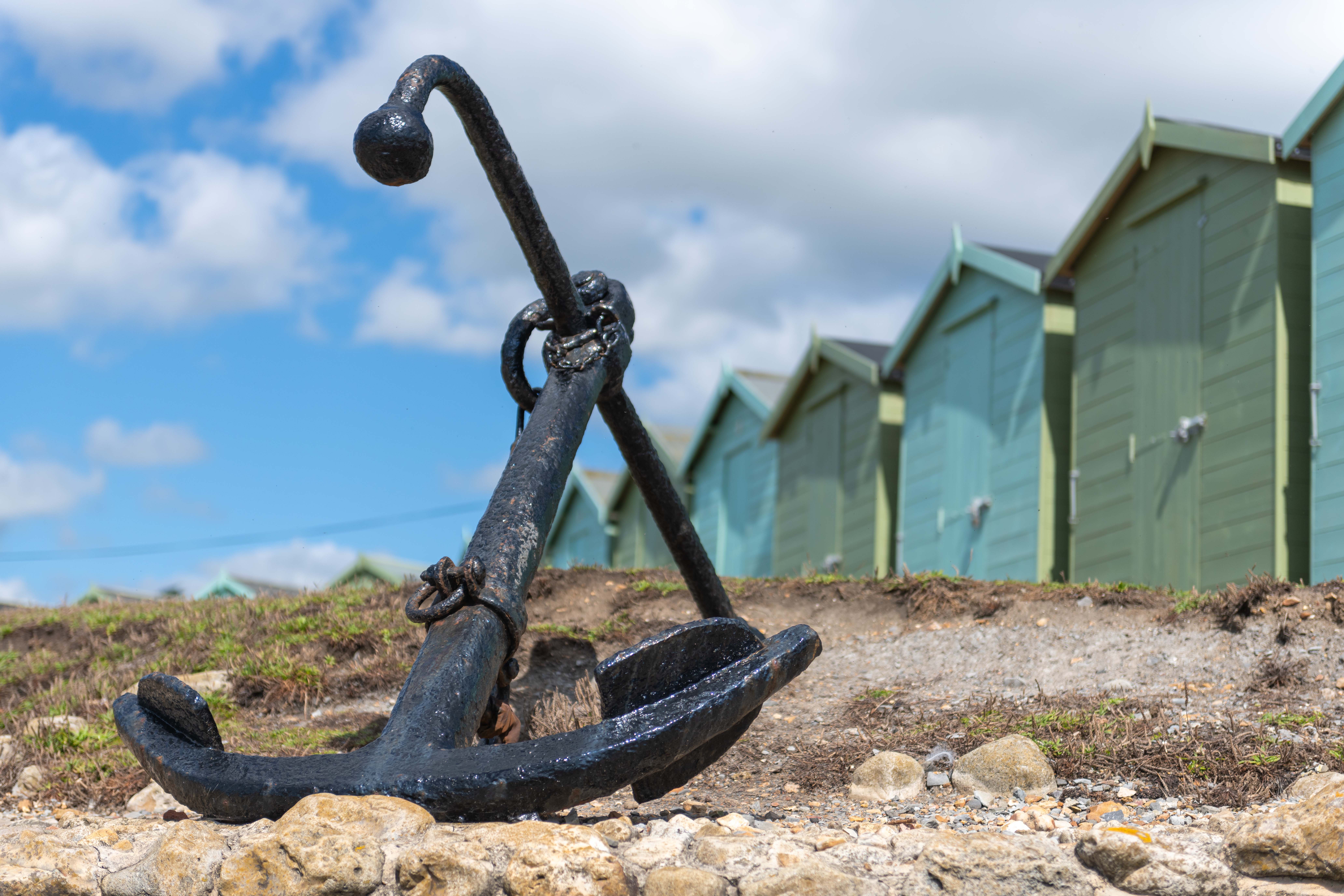 Photo of the anchor at Charmouth beach with beach huts in the background Charmouth, Bridport