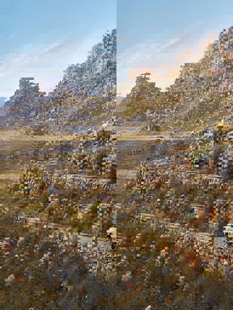 Jeep driving along a gravel path with the Cederberg mountains in the backgrounds Jeep driving along a gravel path with the Cederberg mountains in the backgrounds