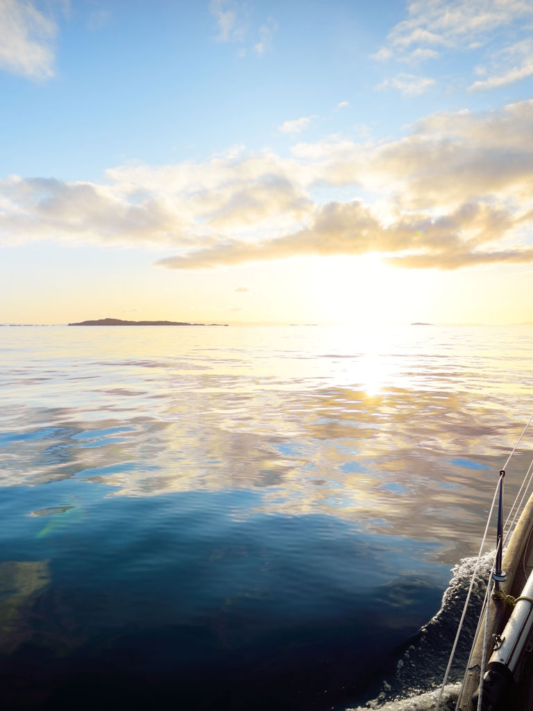 Sloop rigged modern yacht with wooden teak deck sailing at sunrise. A view from the deck to the bow. Colorful clouds. Port Ellen, Isle of Islay, Inner Hebrides, Scotland, UK Port Ellen, Isle of Islay, UK Sloop rigged modern yacht with wooden teak deck sailing at sunrise. A view from the deck to the bow. Colorful clouds. Port Ellen, Isle of Islay, Inner Hebrides, Scotland, UK Port Ellen, Isle of Islay, UK
