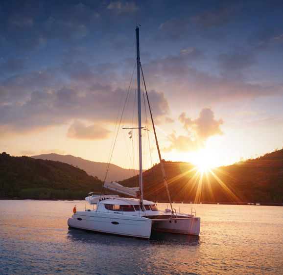 Catamaran in the tropical sea at sunset. Yachting / Luxury Sailing theme. Catamaran in the tropical sea at sunset. Yachting / Luxury Sailing theme.