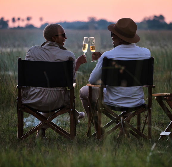 Two men dine in the bush and toast Champagne Two men dine in the bush and toast Champagne