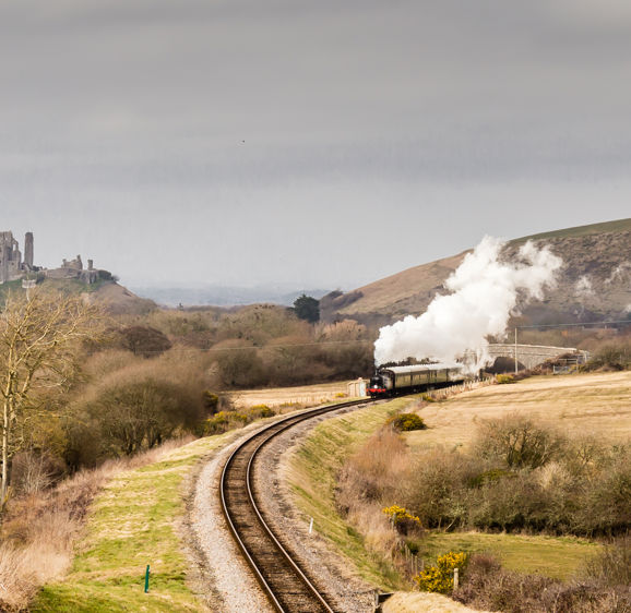 Steam train on the Swanage Railway with Corfe Castle and hills in background Steam train on the Swanage Railway with Corfe Castle and hills in background