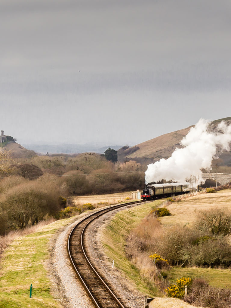 Steam train on the Swanage Railway with Corfe Castle and hills in background Steam train on the Swanage Railway with Corfe Castle and hills in background