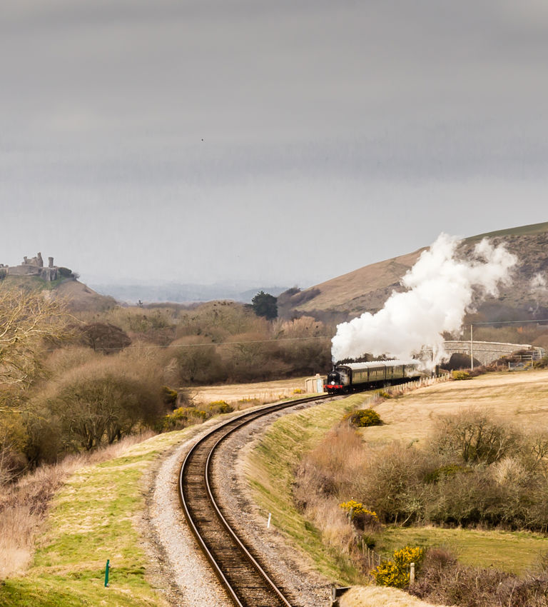 Steam train on the Swanage Railway with Corfe Castle and hills in background Steam train on the Swanage Railway with Corfe Castle and hills in background