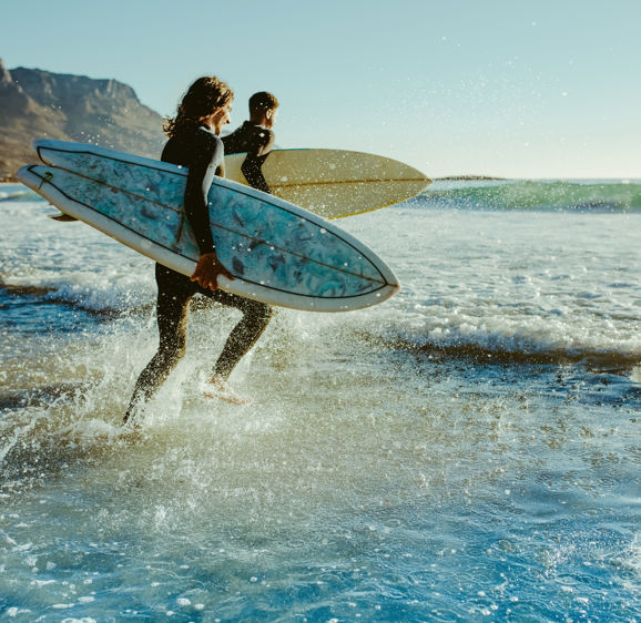 Two male surfers going for surfing in the sea. Two men carrying surfboards running in to the sea for surfing Two male surfers going for surfing in the sea. Two men carrying surfboards running in to the sea for surfing