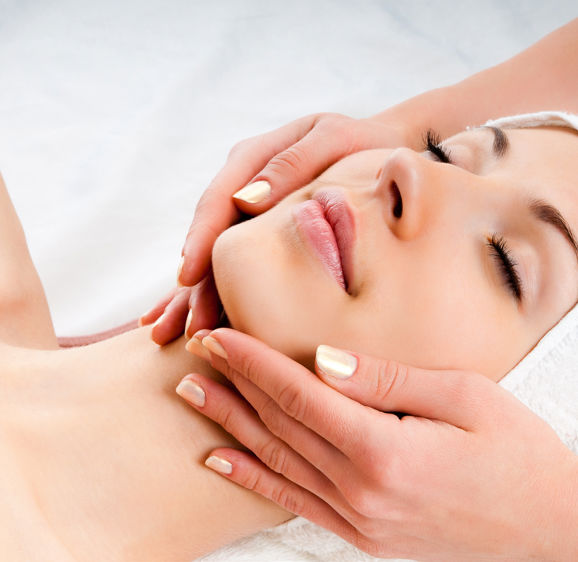 Beautiful young woman receiving facial massage with closed eyes in a spa center Beautiful young woman receiving facial massage with closed eyes in a spa center