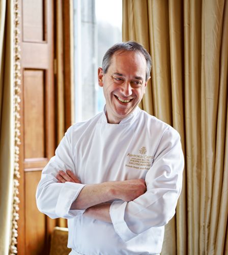 Executive Chef Philippe Farineau standing in front of a window with a drape in the background Executive Chef Philippe Farineau standing in front of a window with a drape in the background